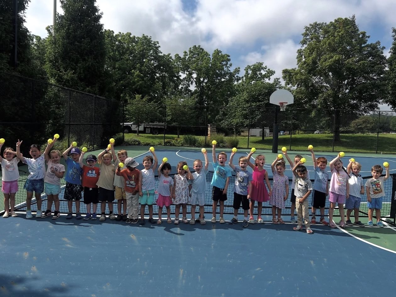 Ready Set Rackets toddlers holding up balls at the net