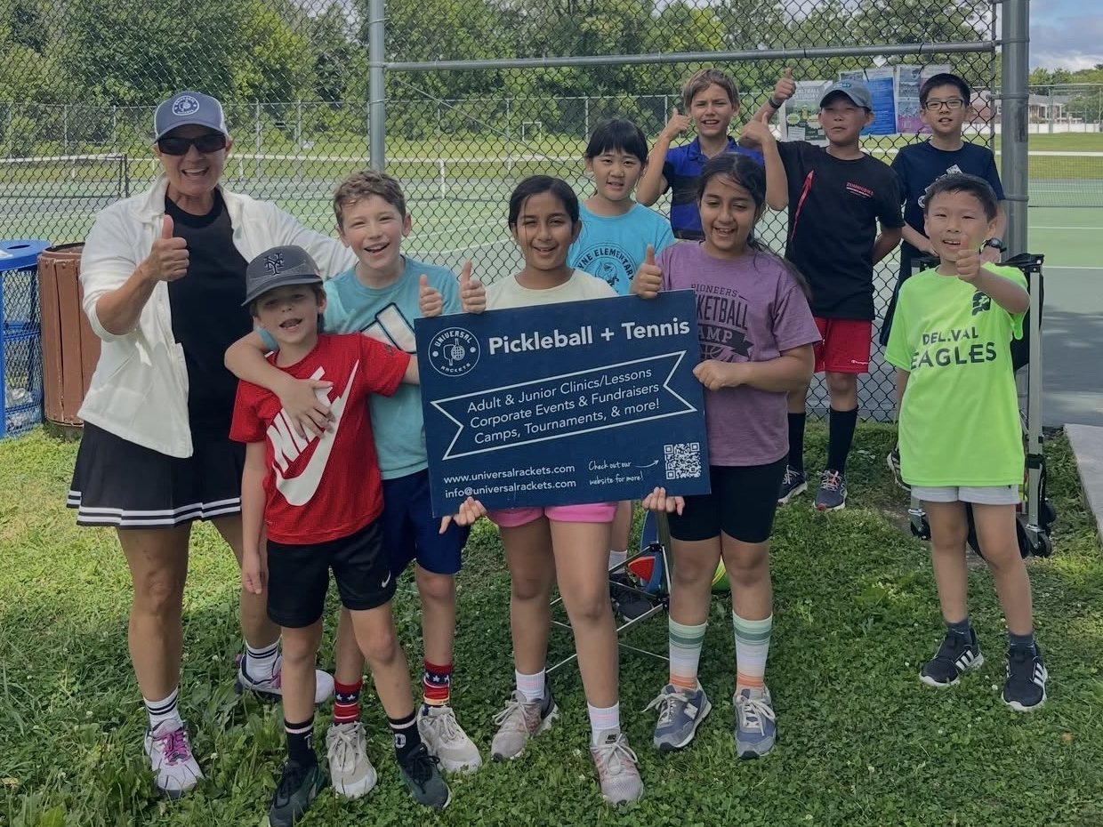 Junior campers holding a Universal Rackets sign with their coach